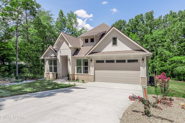 craftsman inspired home with a garage, central air condition unit, and a front yard