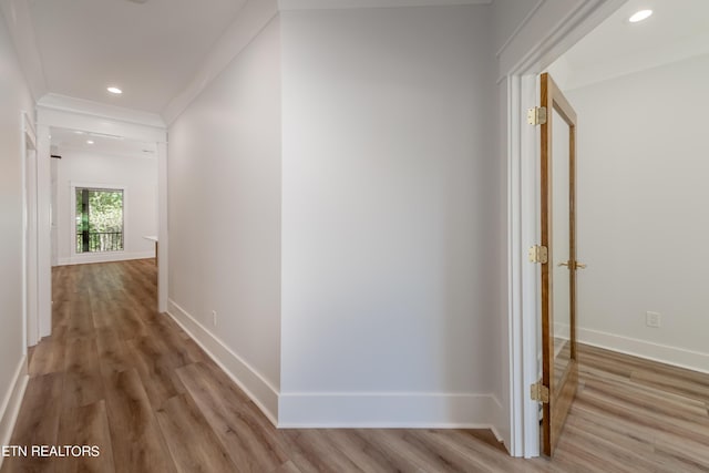 corridor featuring ornamental molding and light hardwood / wood-style floors