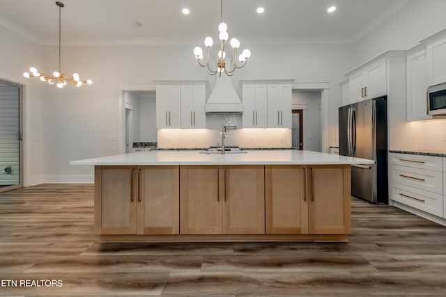 kitchen with white cabinets, stainless steel appliances, a notable chandelier, and a large island with sink