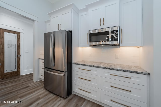 kitchen with white cabinetry, light stone counters, tasteful backsplash, and stainless steel appliances