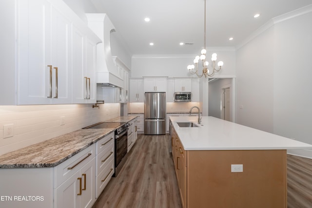 kitchen featuring stainless steel appliances, white cabinetry, and a kitchen island with sink