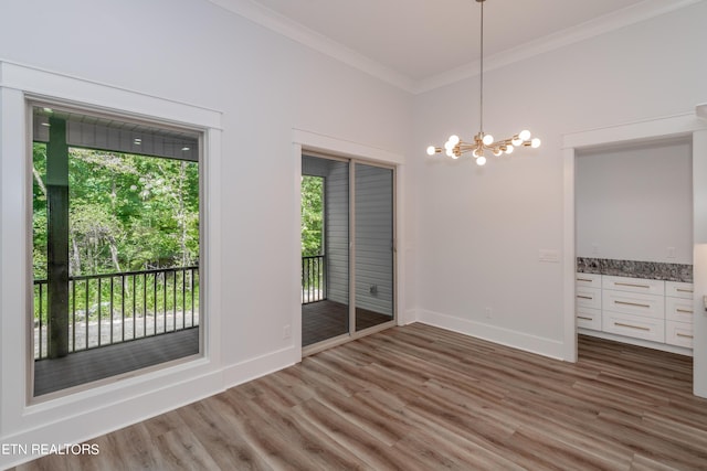 unfurnished dining area featuring dark wood-type flooring, ornamental molding, and an inviting chandelier