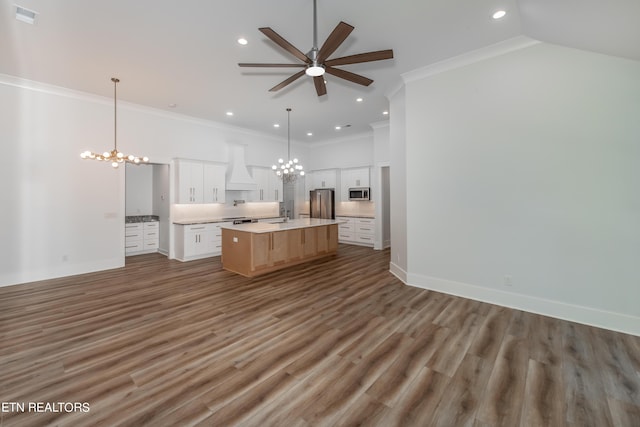 kitchen with decorative light fixtures, white cabinets, a large island, stainless steel appliances, and custom range hood