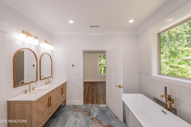 bathroom with vanity, a healthy amount of sunlight, a bath, and crown molding