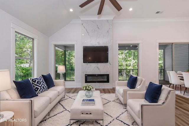 living room with light hardwood / wood-style flooring, a high end fireplace, ornamental molding, and plenty of natural light