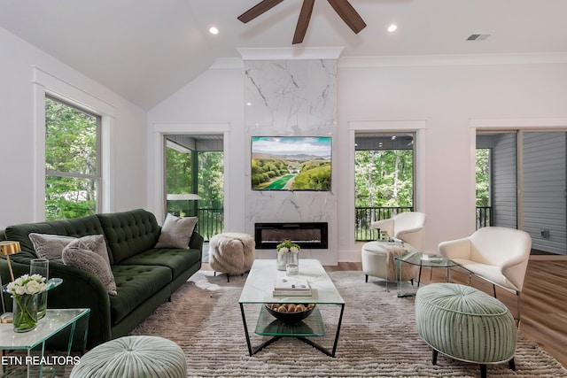 living room featuring crown molding, wood-type flooring, a fireplace, and vaulted ceiling