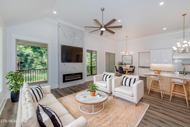 living room with hardwood / wood-style flooring, a high end fireplace, ornamental molding, and ceiling fan with notable chandelier