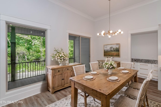 dining space with crown molding, light hardwood / wood-style floors, and a chandelier