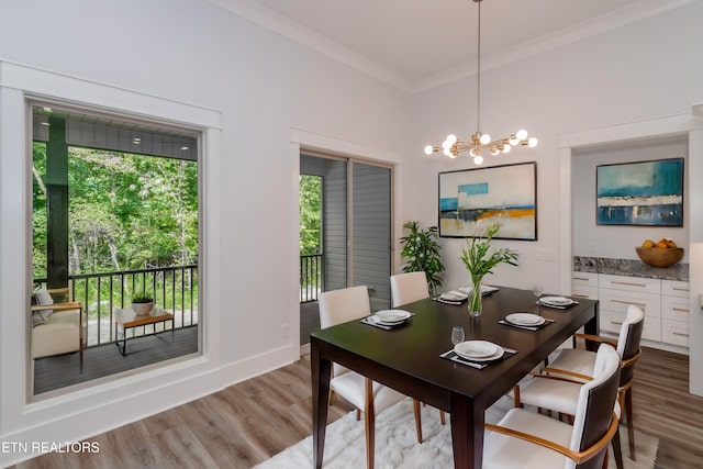 dining area with ornamental molding, a chandelier, and light hardwood / wood-style floors