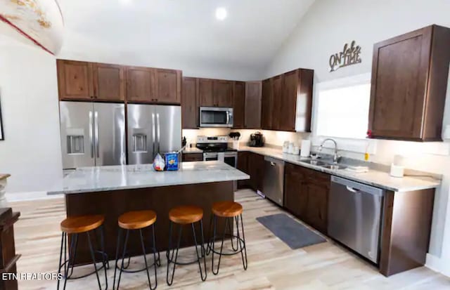 kitchen featuring stainless steel appliances, a kitchen island, lofted ceiling, and light hardwood / wood-style floors