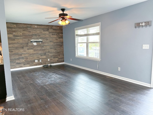 unfurnished room with ceiling fan, dark hardwood / wood-style flooring, and wood walls