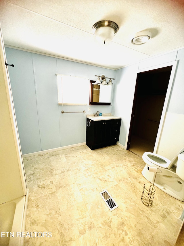 bathroom featuring vanity, toilet, and a textured ceiling