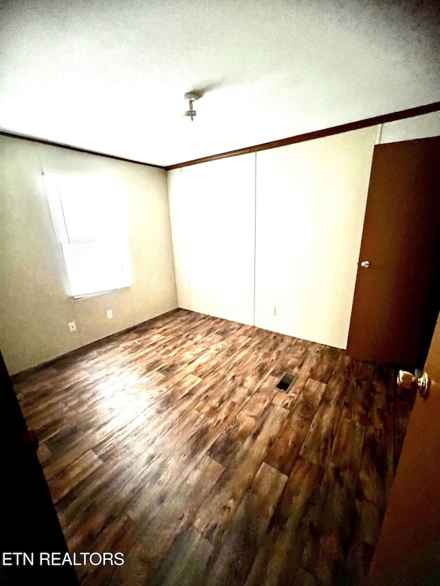 unfurnished bedroom with a closet, ornamental molding, hardwood / wood-style flooring, and a textured ceiling