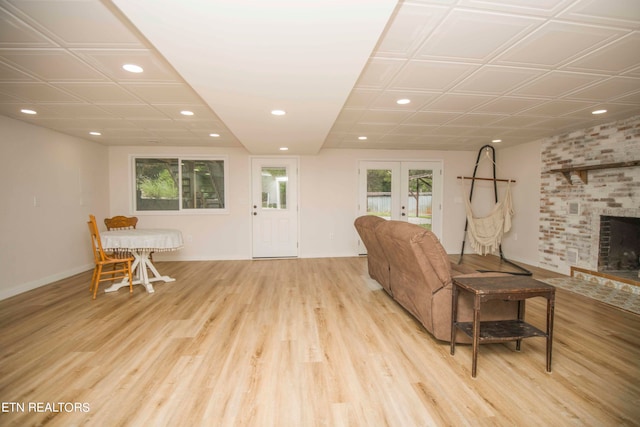 living room featuring light hardwood / wood-style flooring, french doors, and a brick fireplace