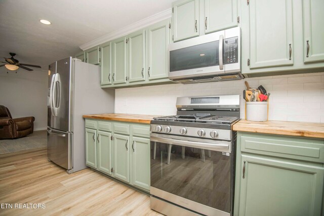 kitchen featuring stainless steel appliances, decorative backsplash, light wood-type flooring, ceiling fan, and wooden counters