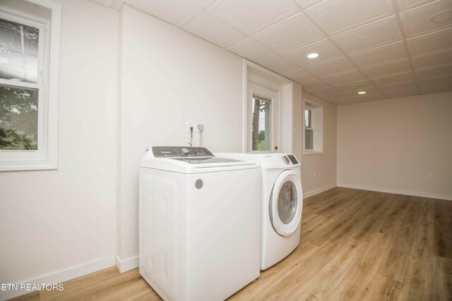 clothes washing area with light wood-type flooring and separate washer and dryer