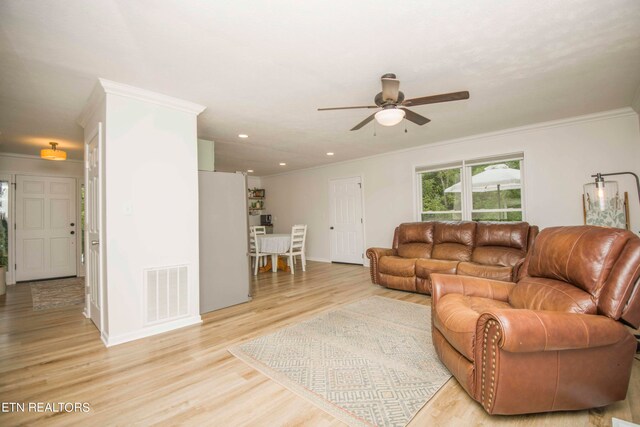 living room featuring ceiling fan, light wood-type flooring, and ornamental molding