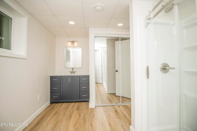 interior space with hardwood / wood-style flooring, a drop ceiling, and vanity