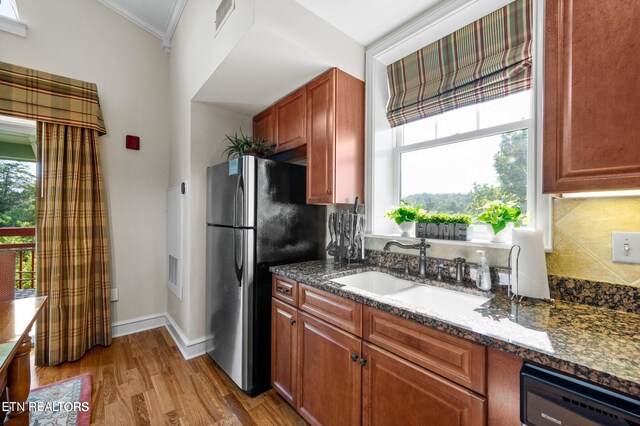 kitchen with dishwashing machine, light wood-type flooring, sink, and a wealth of natural light