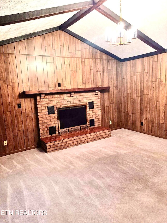 unfurnished living room featuring wood walls, an inviting chandelier, carpet floors, a fireplace, and vaulted ceiling with beams