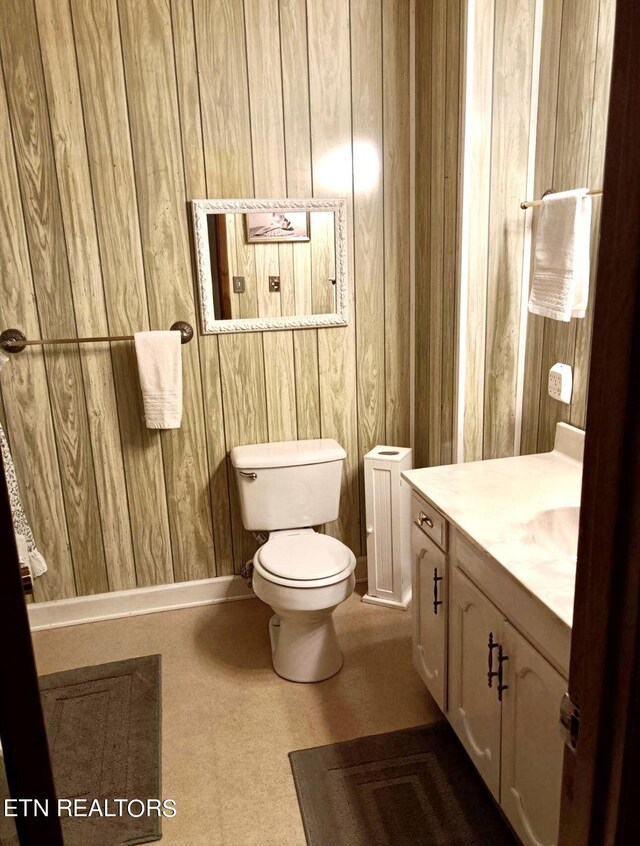 bathroom featuring toilet, wooden walls, vanity, and radiator