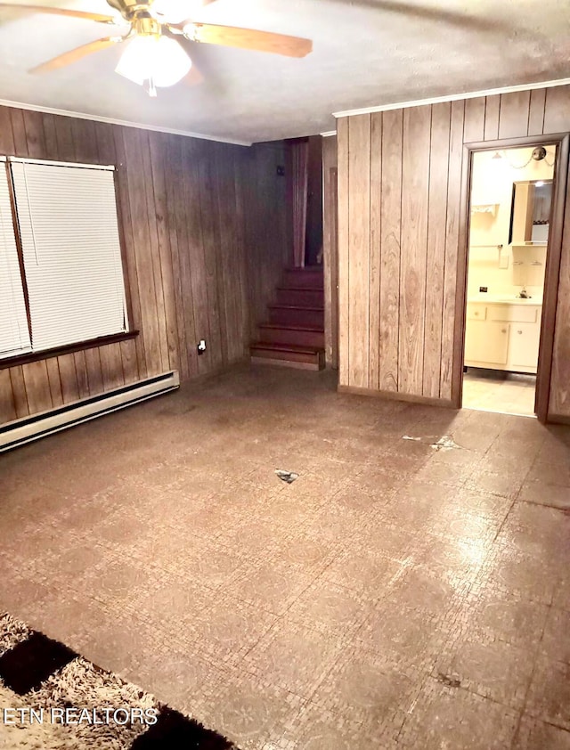 unfurnished room featuring ceiling fan, wooden walls, and a baseboard radiator