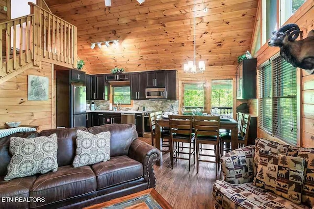 living room with wood walls, high vaulted ceiling, wood-type flooring, and a chandelier