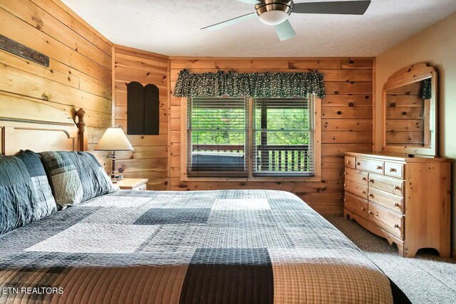 carpeted bedroom with wood walls and ceiling fan