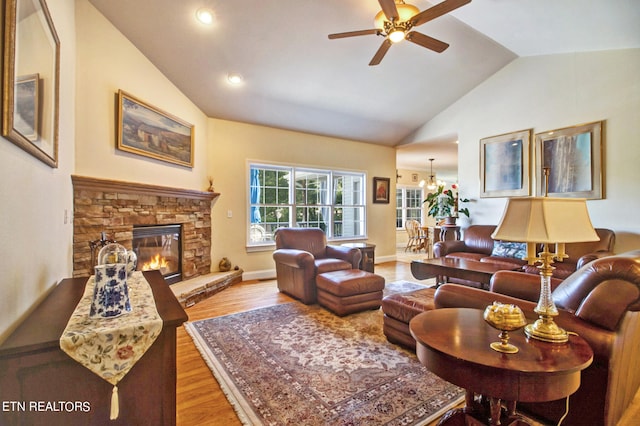 living room with lofted ceiling, hardwood / wood-style floors, a fireplace, and ceiling fan