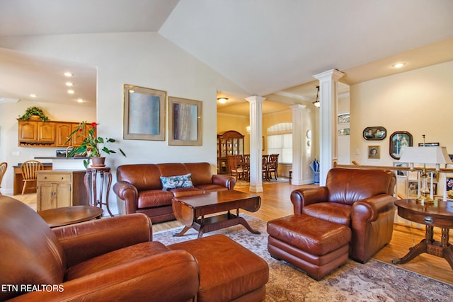 living room featuring lofted ceiling, light wood-type flooring, and ornate columns