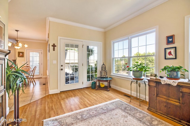 doorway to outside with hardwood / wood-style flooring, crown molding, and a notable chandelier