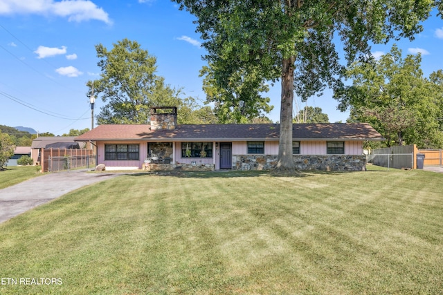 ranch-style house with board and batten siding, a chimney, a front yard, and fence