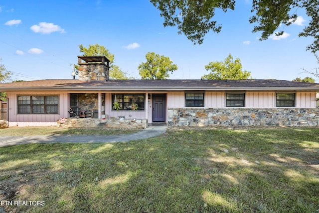 view of front of home with stone siding, a chimney, board and batten siding, and a front lawn