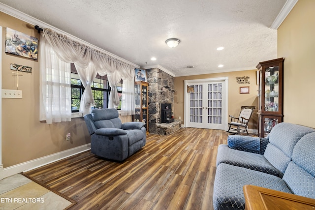 living room featuring a textured ceiling, crown molding, a stone fireplace, and hardwood / wood-style flooring