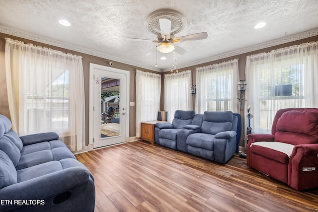 living room with hardwood / wood-style flooring, ornamental molding, a textured ceiling, and ceiling fan