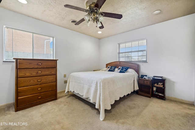 bedroom featuring a textured ceiling, ceiling fan, and light carpet