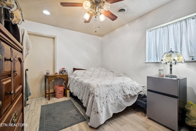 bedroom featuring ceiling fan, light hardwood / wood-style floors, and a textured ceiling