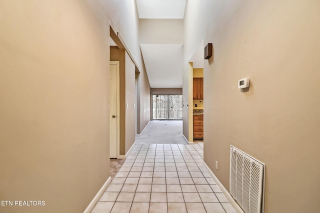 hall featuring a high ceiling and light tile patterned floors