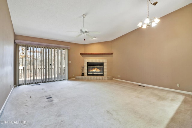 unfurnished living room with ceiling fan with notable chandelier, a brick fireplace, light colored carpet, and a textured ceiling