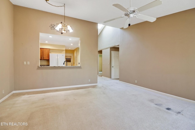 unfurnished living room featuring ceiling fan with notable chandelier, sink, and light carpet