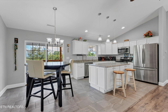 kitchen featuring pendant lighting, light hardwood / wood-style floors, light stone countertops, a center island, and stainless steel appliances