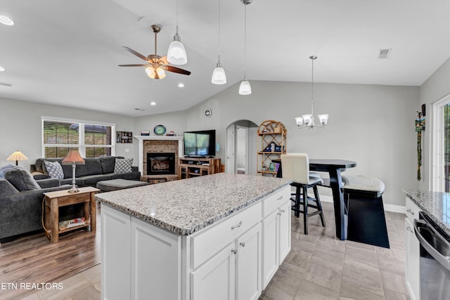 kitchen featuring light hardwood / wood-style flooring, ceiling fan with notable chandelier, vaulted ceiling, a kitchen island, and white cabinets