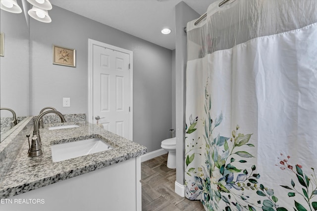 bathroom featuring toilet and dual bowl vanity