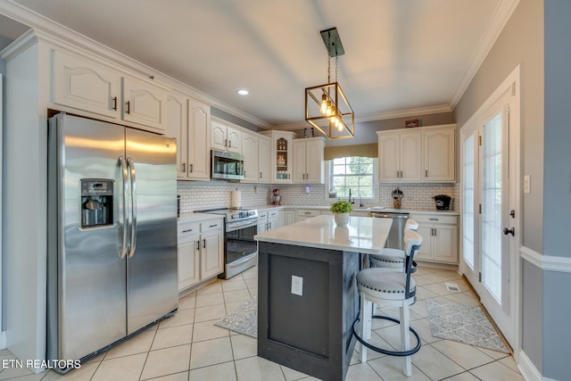 kitchen featuring a kitchen island, tasteful backsplash, white cabinets, light tile patterned floors, and stainless steel appliances