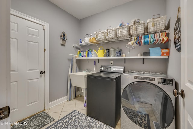 laundry room with independent washer and dryer and light tile patterned floors