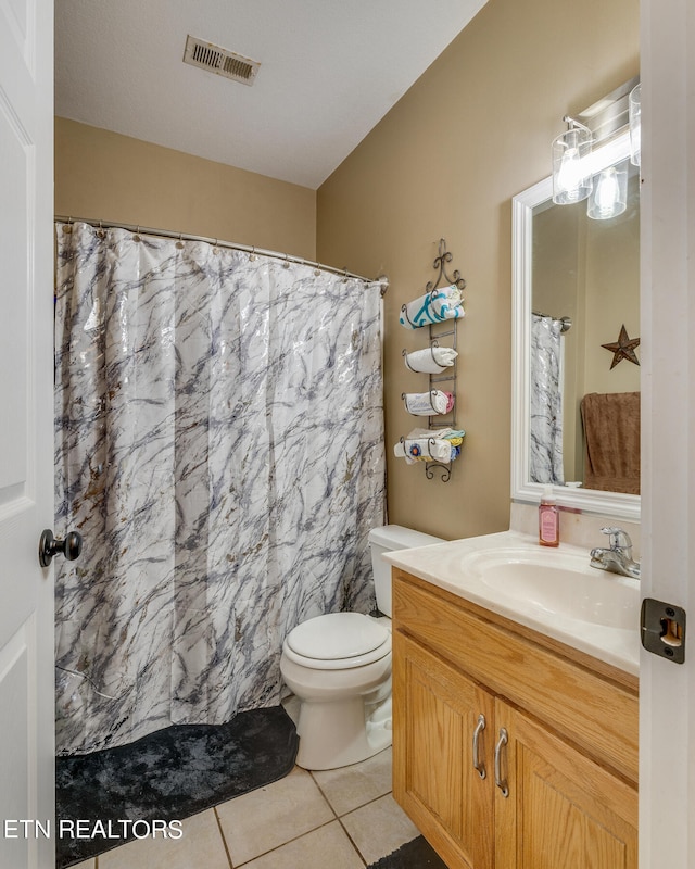 bathroom with toilet, vanity, and tile patterned floors