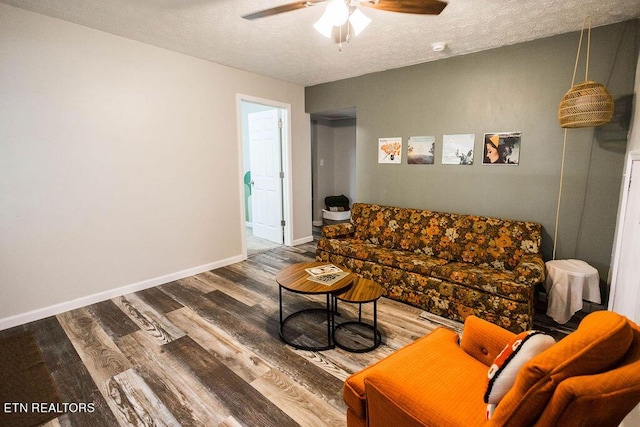 living room featuring a textured ceiling, wood finished floors, a ceiling fan, and baseboards