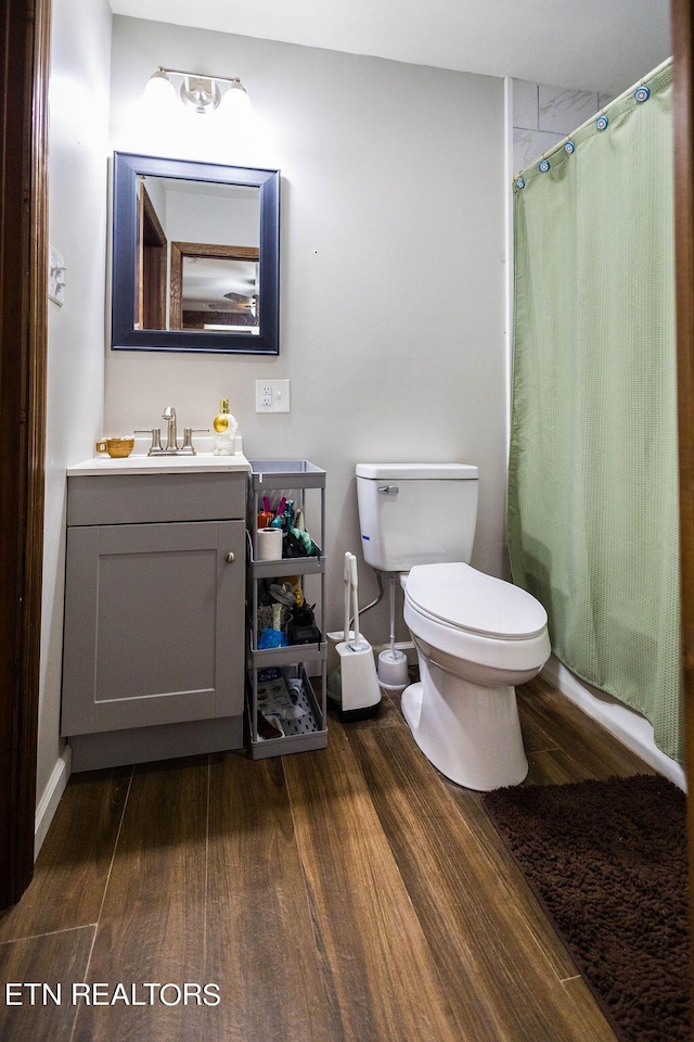 bathroom with toilet, curtained shower, wood finished floors, and vanity