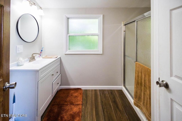 bathroom featuring a shower stall, baseboards, wood finished floors, and vanity