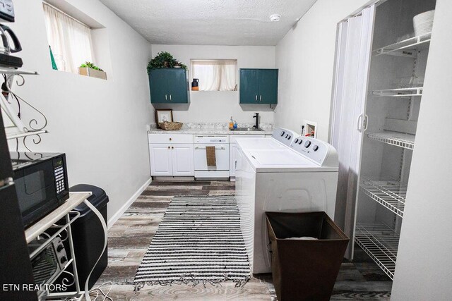 laundry room with dark hardwood / wood-style flooring, cabinets, washer and clothes dryer, sink, and a textured ceiling